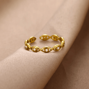 Gold evil eye ring with colorless gemstones on a beige background