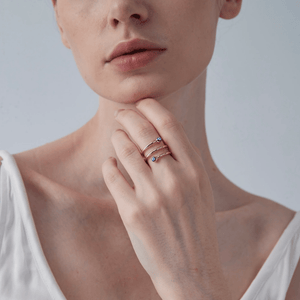 Woman wearing a gold three row ring with blue evil eye charms on a light gray background