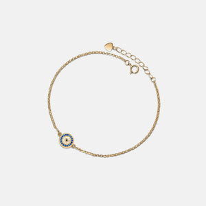 Gold bracelet with a small round charm on a light beige background