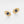 Pair of gold evil eye earrings with blue and white gemstones on a light gray background