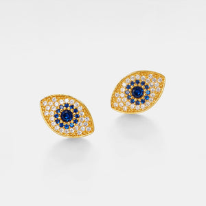 Pair of gold evil eye earrings with blue and white gemstones on a light gray background