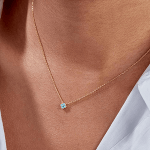 Gold necklace with a blue gemstone on a person's neck
