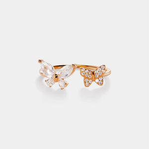 Butterfly-shaped ring with rose gold frame and clear gemstone on a white background