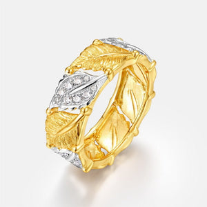 Gold and silver ring with leaf design on a light gray background