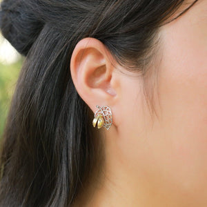 Close-up of an ear wearing a silver earring with a blurred background