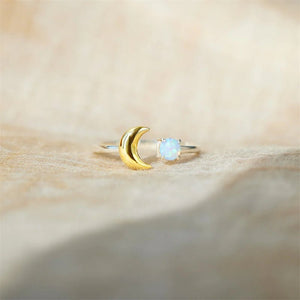 Gold ring with a moon design and opal stone on a beige fabric background