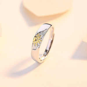Silver ring with gold sun accents on a light beige background