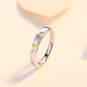 Silver ring with gold moon and star accents on a light beige background