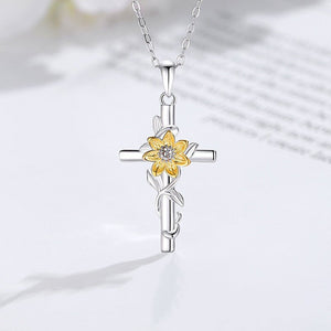 Silver cross pendant with a yellow flower design on a white background