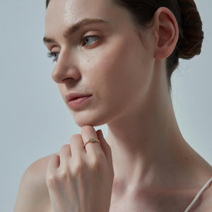 Woman with a ring on her finger against a plain background