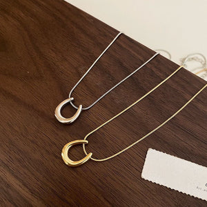 Two necklaces with unique pendants on a wooden surface.