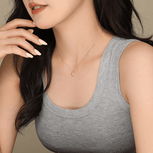 Woman wearing a gray tank top and gold necklace against a neutral background