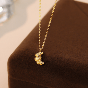 Gold necklace with a butterfly pendant on a brown surface