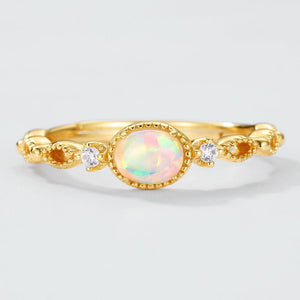 Gold ring with an opal stone and small diamonds on a light gray background
