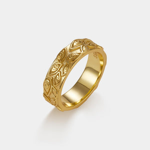 Gold ring with evil eye patterns on a light gray background