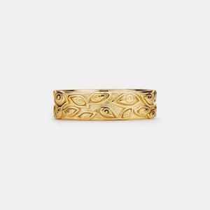 Gold ring with evil eye patterns on a white background