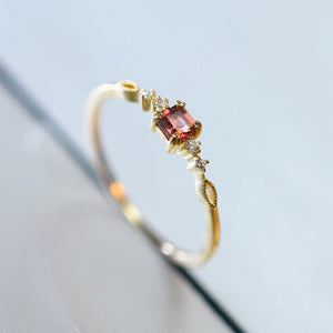 Gold ring with a red gemstone on a light blue background