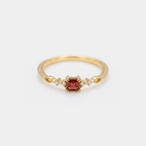 Gold ring with a red gemstone on a white background