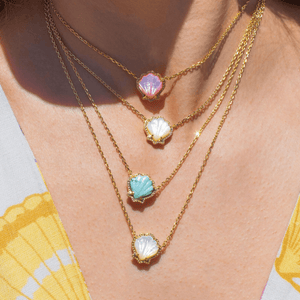 Necklace with colorful shell-shaped pendants on a person wearing a yellow top.
