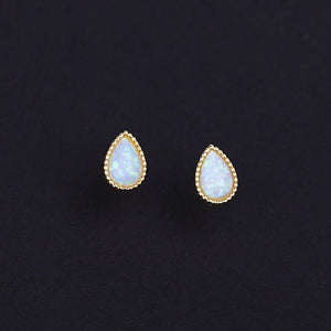 A set of vintage teardrop cut opal stud earrings with one pair showcasing a silver setting and another with a gold plating, displayed on a dark background.