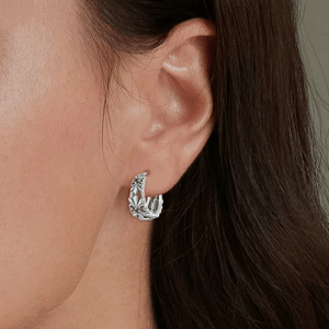 Silver hoop earring worn by a person with dark hair.