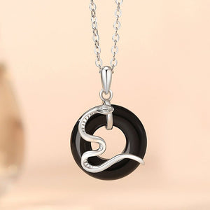 Silver and black pendant necklace on a beige background
