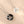 Two silver necklaces with circular pendants on a beige background