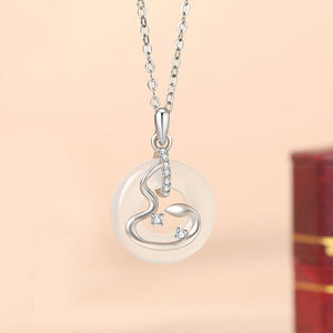 Silver necklace with a round pendant on a beige background
