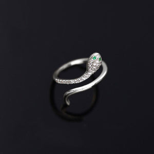 A silver-colored bypass ring with a snake design, featuring cubic zirconia, displayed on a black background.