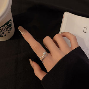 Model wearing a silver snake-shaped ring with gemstones on a gray background