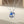 Silver necklace with a blue pendant on a beige background