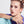 A young woman with her hair styled in two buns poses while wearing a silver-cased wristwatch. The watch face features a vibrant, artistic painting reminiscent of Van Gogh's 