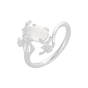 Silver ring with a white gemstone and floral designs on a white background