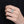 Hand wearing a silver ring with gemstones on a black background