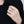 Hand wearing a silver ring with a diamond on a black background