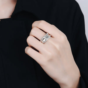 Hand wearing a silver ring with a diamond on a black background