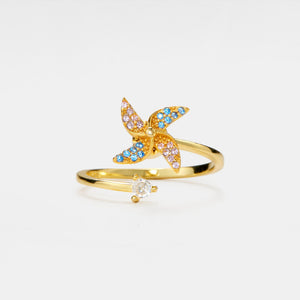 Gold ring with butterfly design and small gemstone on a white background