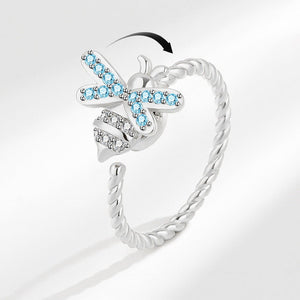 A silver-colored fidget spinner ring with a bee design, featuring blue cubic zirconia stones, on a white background.