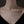 Silver necklace with a star-shaped pendant on a person's neck against a dark background