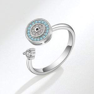 Silver evil eye spinner ring with blue gemstones and a diamond on a white background