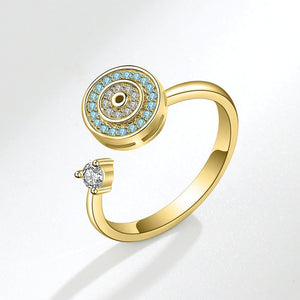 Gold evil eye spinner ring with blue gemstones and a diamond on a white background