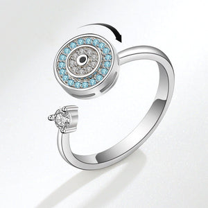 Silver evil eye spinner ring with blue gemstones and a diamond on a white background