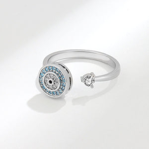 Silver evil eye spinner ring with blue gemstones and a diamond on a white background