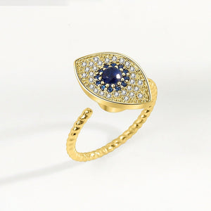 A gold ring with a large blue and clear cubic zirconia evil eye-shaped inset, designed as a fidget spinner.