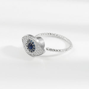 A silver ring with a large blue and clear cubic zirconia evil eye-shaped inset, designed as a fidget spinner.