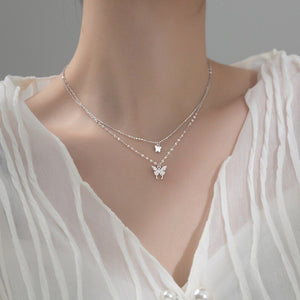 Silver butterfly necklace on a mannequin with a white blouse
