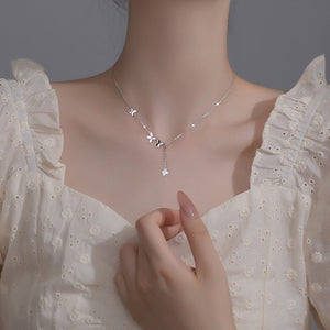 Silver necklace with floral pendant on a mannequin wearing a white dress.