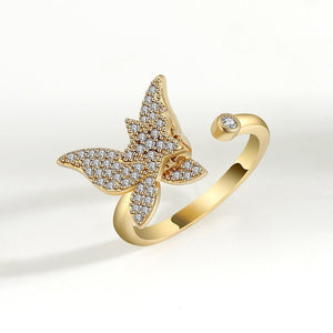 Gold spinner ring with diamond-encrusted butterfly design on a white background