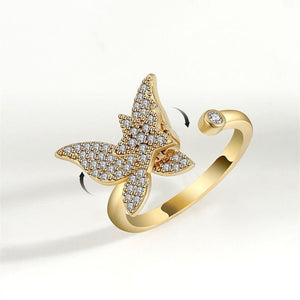 Gold spinner ring with diamond-encrusted butterfly design on a white background