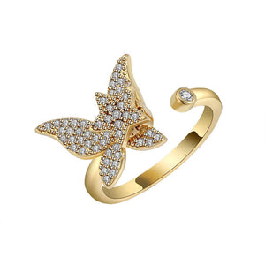 Gold spinner ring with diamond-encrusted butterfly design on a white background